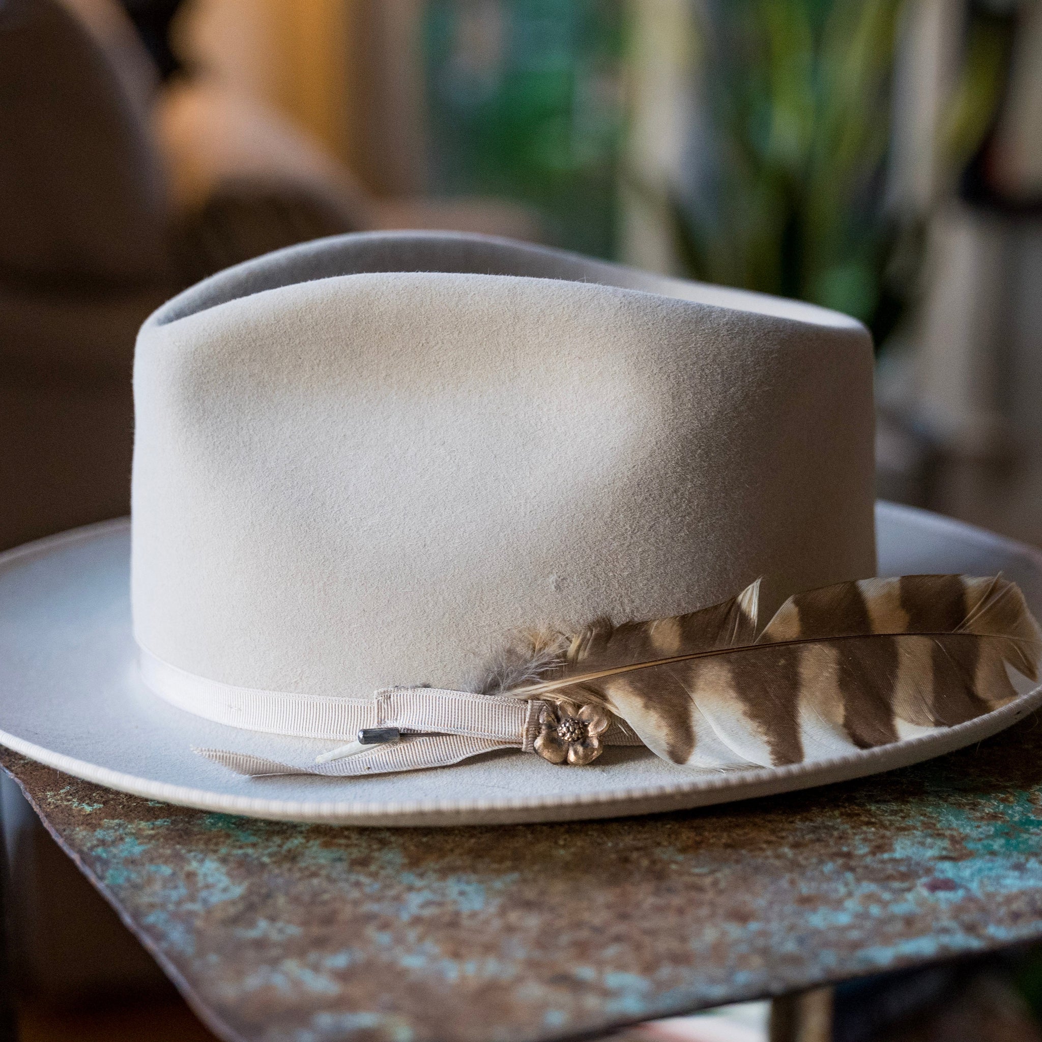 White fedora hat with a feather on a rustic wooden table