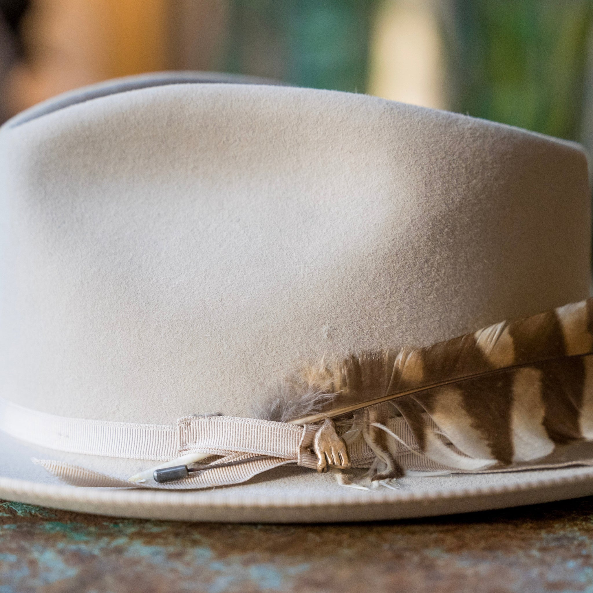 White fedora hat with a feather on a rustic surface